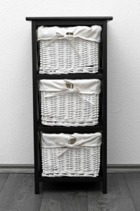 brown shelf with wicker baskets at white wall