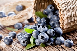 Blueberries have dropped from the basket on an old wooden table.